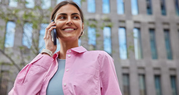 Dame i rosa skjorte som snakker i telefonen