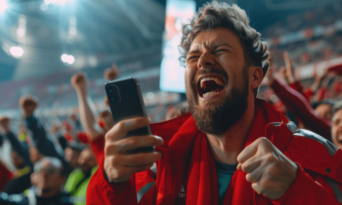 Mann på fotballkamp med telefon