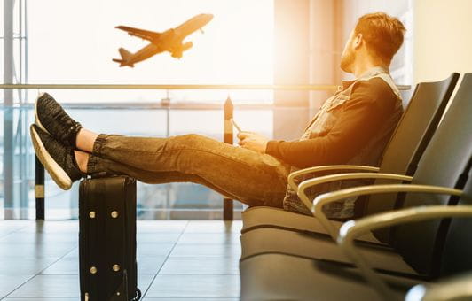 Mann sitter på gaten til å rekke et fly, mens han ser ut av vinduet