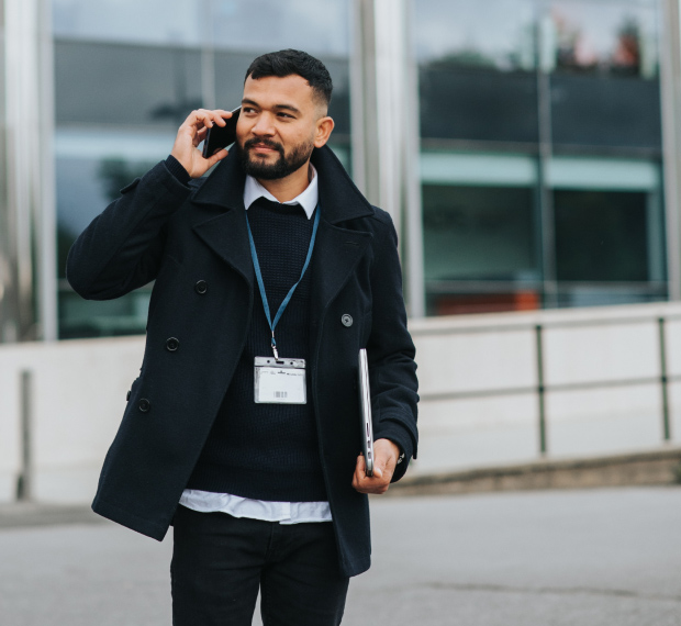 Mann som snakker i telefon med ansatt-kort hengende rundt halsen