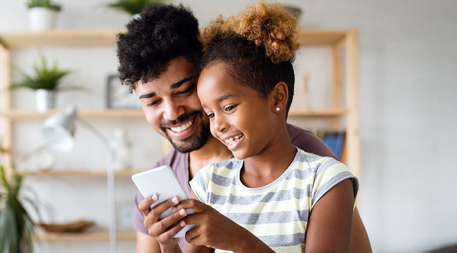 Far og datter som ser på telefon