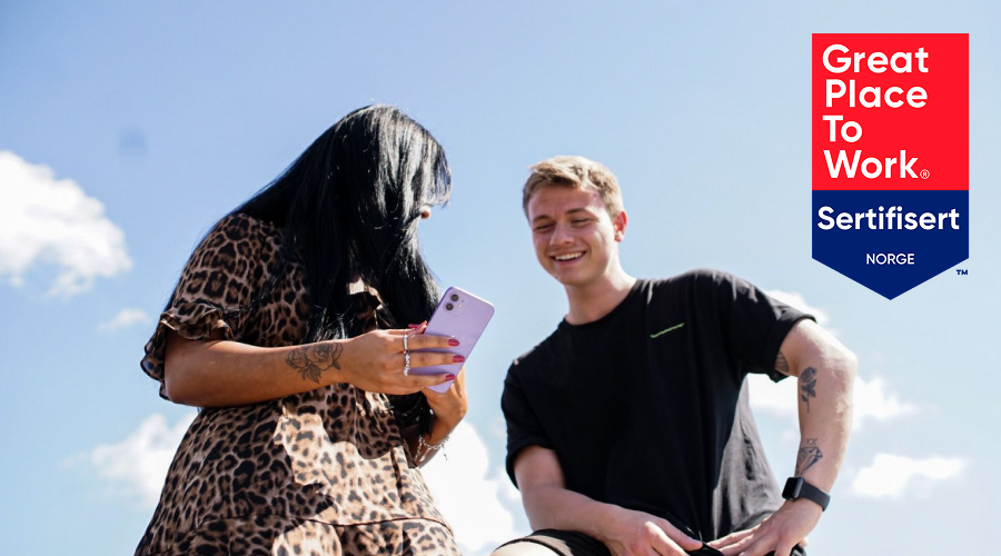 Bilde av to som ser på telefon med great place to work sertifisering