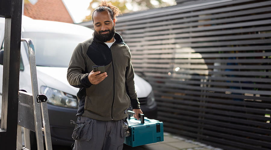 Bilde av en håndverker som ser på telefonen