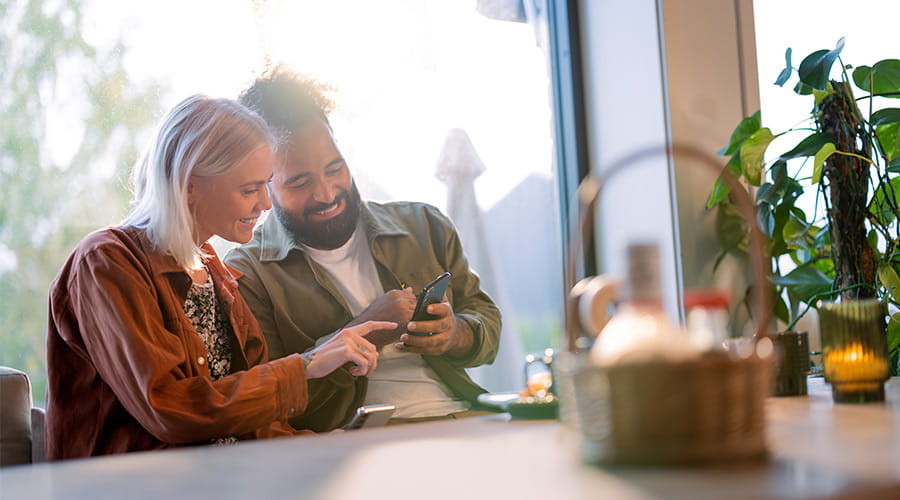 Kjærestepar på kafé som ser på mobilen