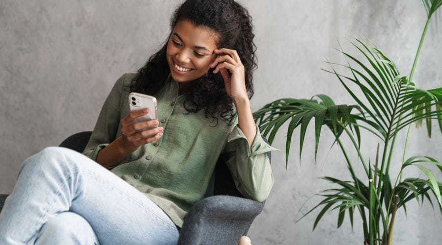 Dame som ser på telefonen og smiler