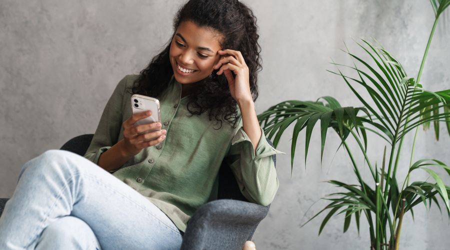 Dame som ser på telefonen og smiler