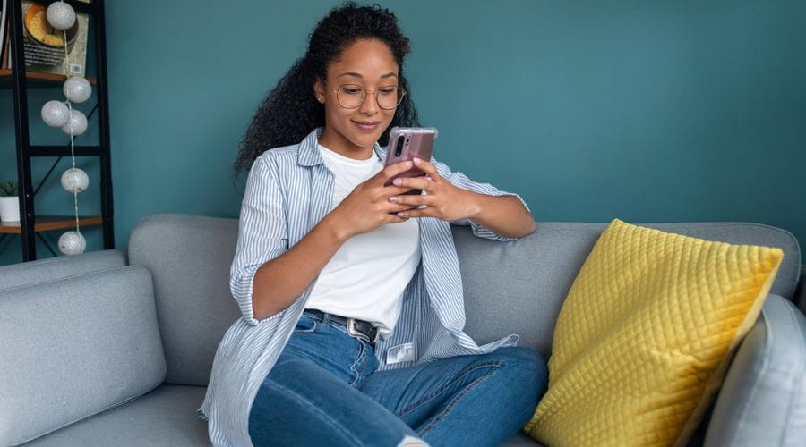 Dame sitter i sofa mens hun ser på mobilen sin