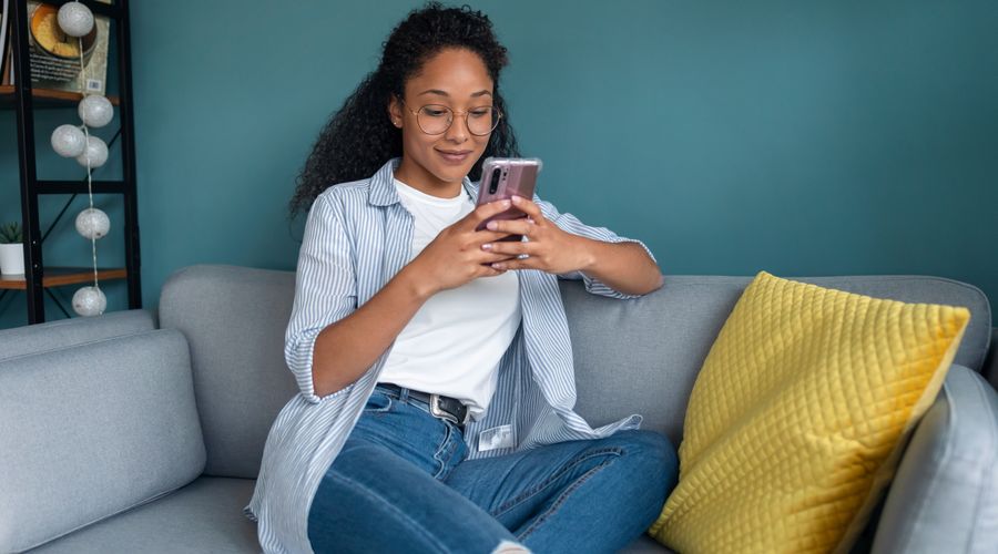 Dame sitter i sofa mens hun ser på mobilen sin