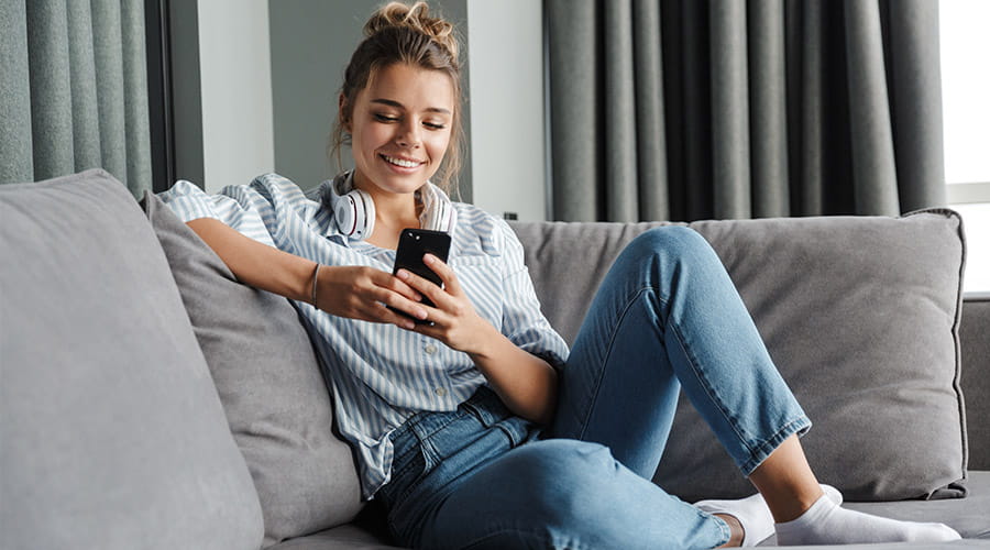 Dame som ser på telefon på sofaen