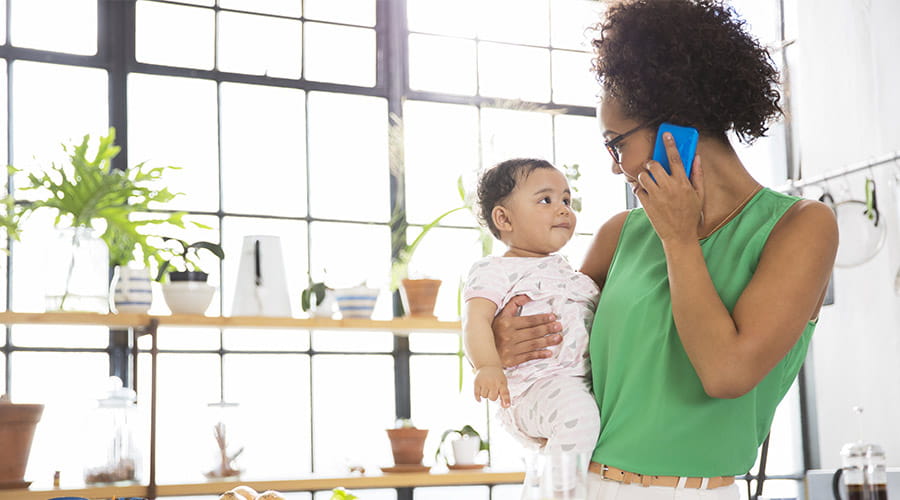 Mor i telefon som holder baby