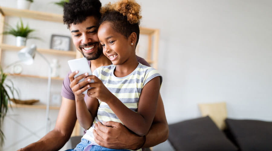 Far og datter som ser på mobil sammen