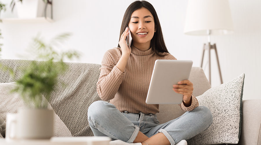 Dame som sitter i en telefonsamtale, mens hun ser på nettbrettet sitt