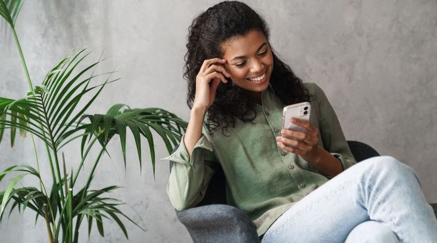 Dame som smiler mens hun ser på telefonen