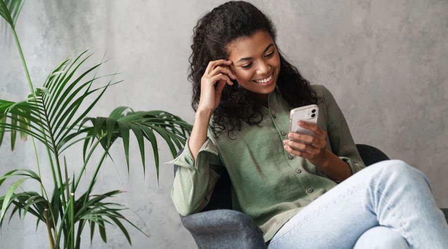 Dame som smiler mens hun ser på telefonen