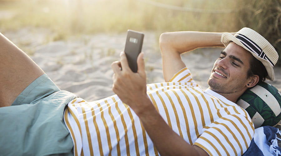 Mann som ligger på stranden med en stråhatt