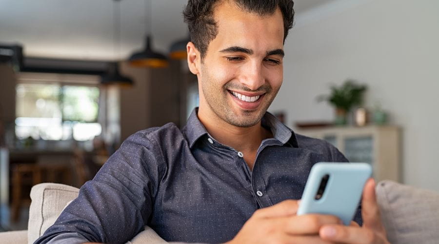 Mann sitter og ser på mobilen sin