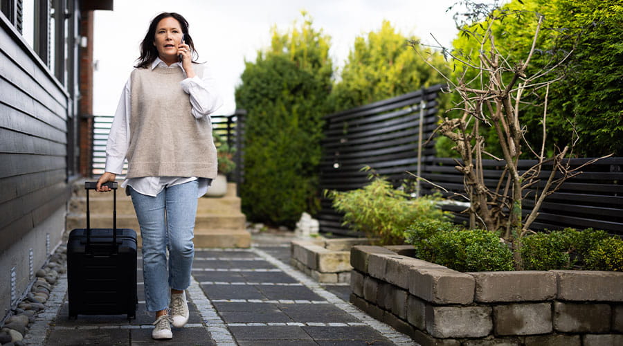 Dame som snakker i telefonen og triller en koffert