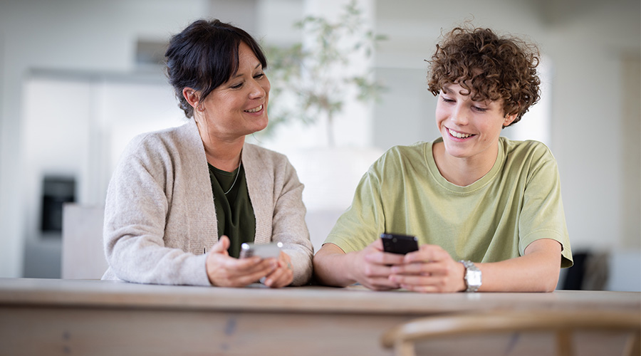 Mor og sønn som sitter å ser på telefonen