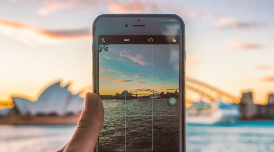 Mobil som tar bilde av opera house i Sidney i solnedgangen