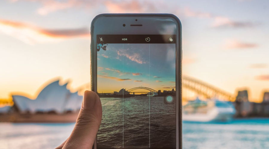 Mobil som tar bilde av opera house i Sidney i solnedgangen