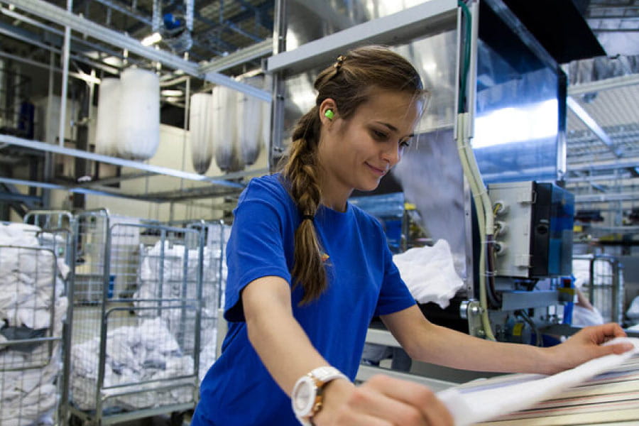 Dame bretter et laken på et stort vaskeri